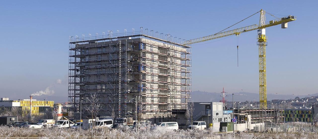 Offenes Feld mit Hochhaus im Bau und Kran.