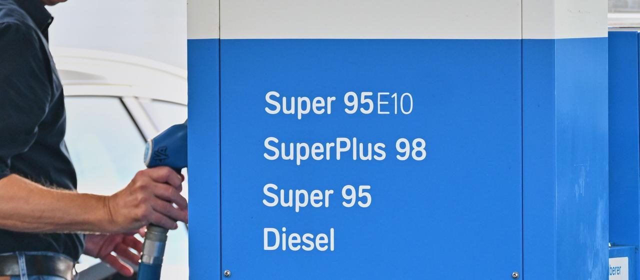 Ein Mann greift an einer Tankstelle nach einem Zapfhahn.
