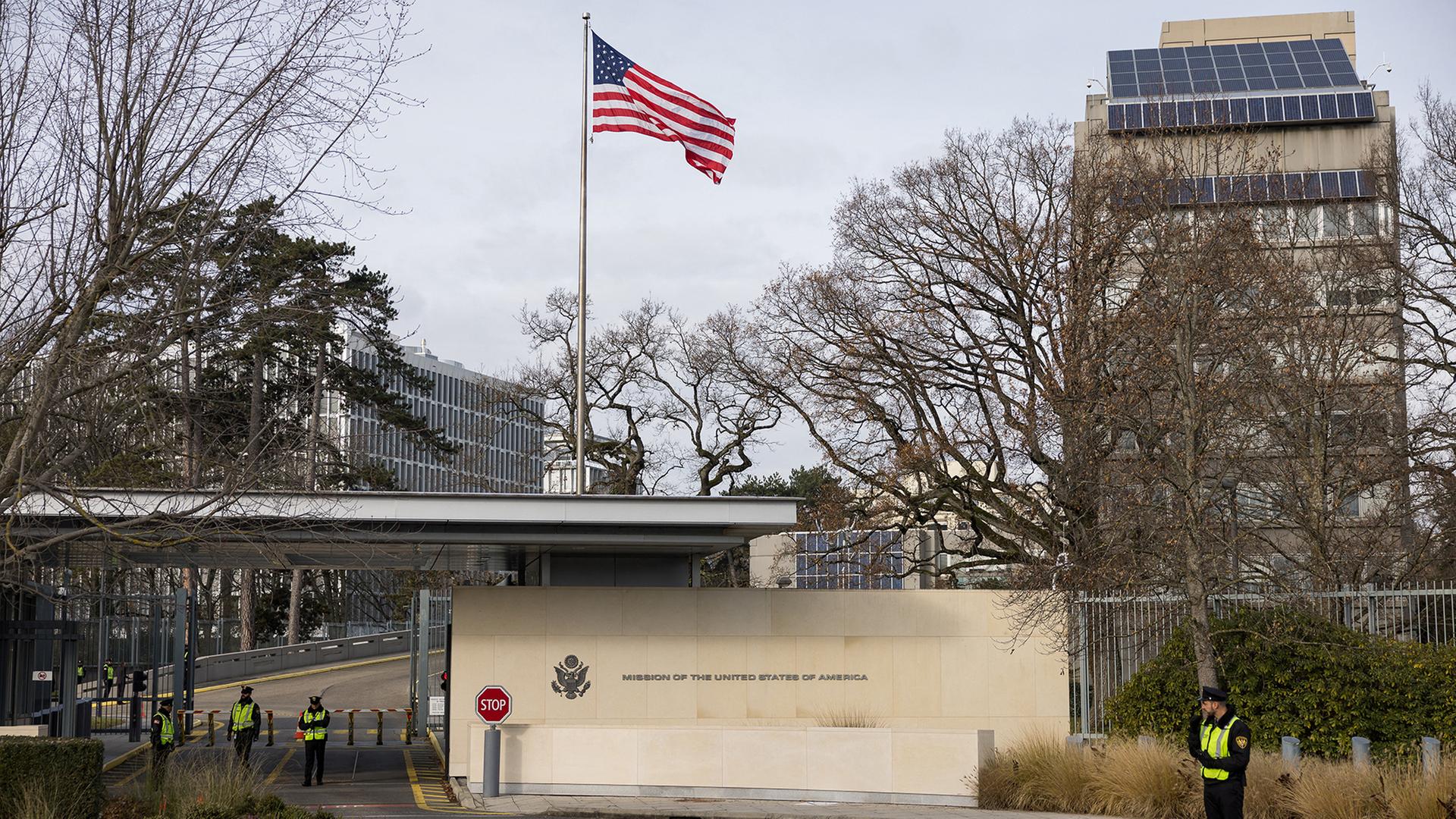 Polizisten stehen vor der Einfahrt eines Gebäudes mit der Aufschrift 