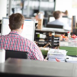 Menschen arbeiten in einem Großraumbüro am Computer.