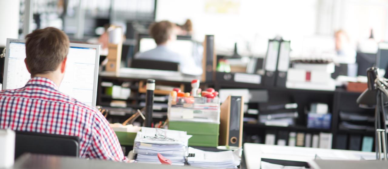 Menschen arbeiten in einem Großraumbüro am Computer.