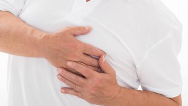 Ein Mann greift mit den Händen auf seinen Brustkorb.