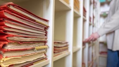 Eine Frau räumt Akten in ein Regal.