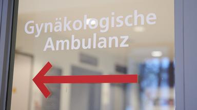 "Gynäkologische Ambulanz" steht über einem Richtungspfeil auf einer Scheibe eines Klinikums. 