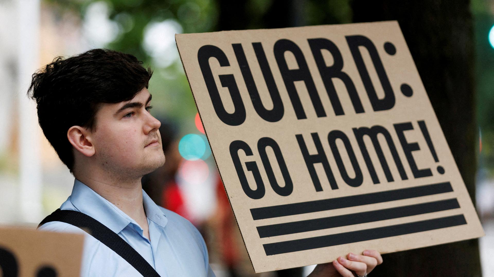 Ein Mann hält ein Schild in Portland in die Höhe, auf dem steht, Guard Go Home  | REUTERS
