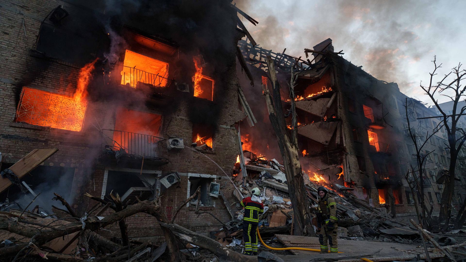 Ein Gebäude in der Ukraine steht nach einem russischen Angriff in Flammen. | Evgeniy Maloletka/AP/dpa