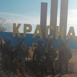 Maskierte Söldner in Tarnanzügen vor einem Ortsschild