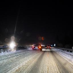 Autos fahren während Schneefalls auf einer Autobahn bei Kiel.