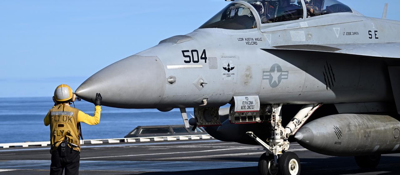 Ein Soldat weißt einen Kampfjet des Typs F 18 an Bord des Flugzeugträger USS Gerald R. Ford ein.