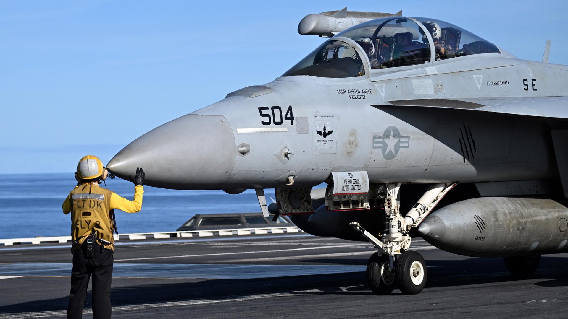 Ein Soldat weißt einen Kampfjet des Typs F 18 an Bord des Flugzeugträger USS Gerald R. Ford ein. | dpa