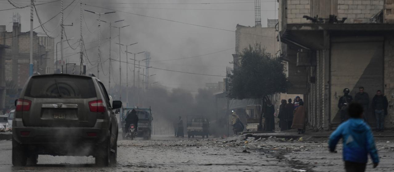 Eine Straße in Tabka in Syrien - im Hintergrund steigt dunkler Rauch.
