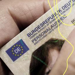 Eine Frau hält einen modernen Personalausweis der Bundesrepublik Deutschland im Scheckkartenformat in ihrer Hand.