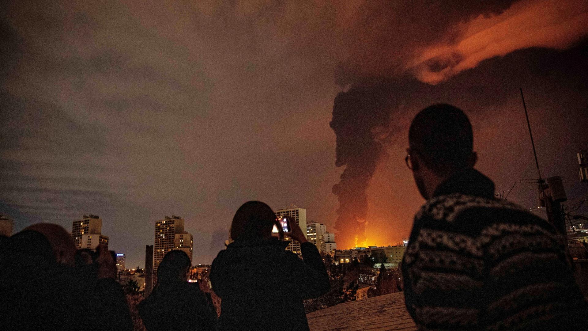 Menschen in Teheran machen Fotos von einer riesigen Rauchsäule, die von einem brennenden Öllager ausgehen soll. | AP