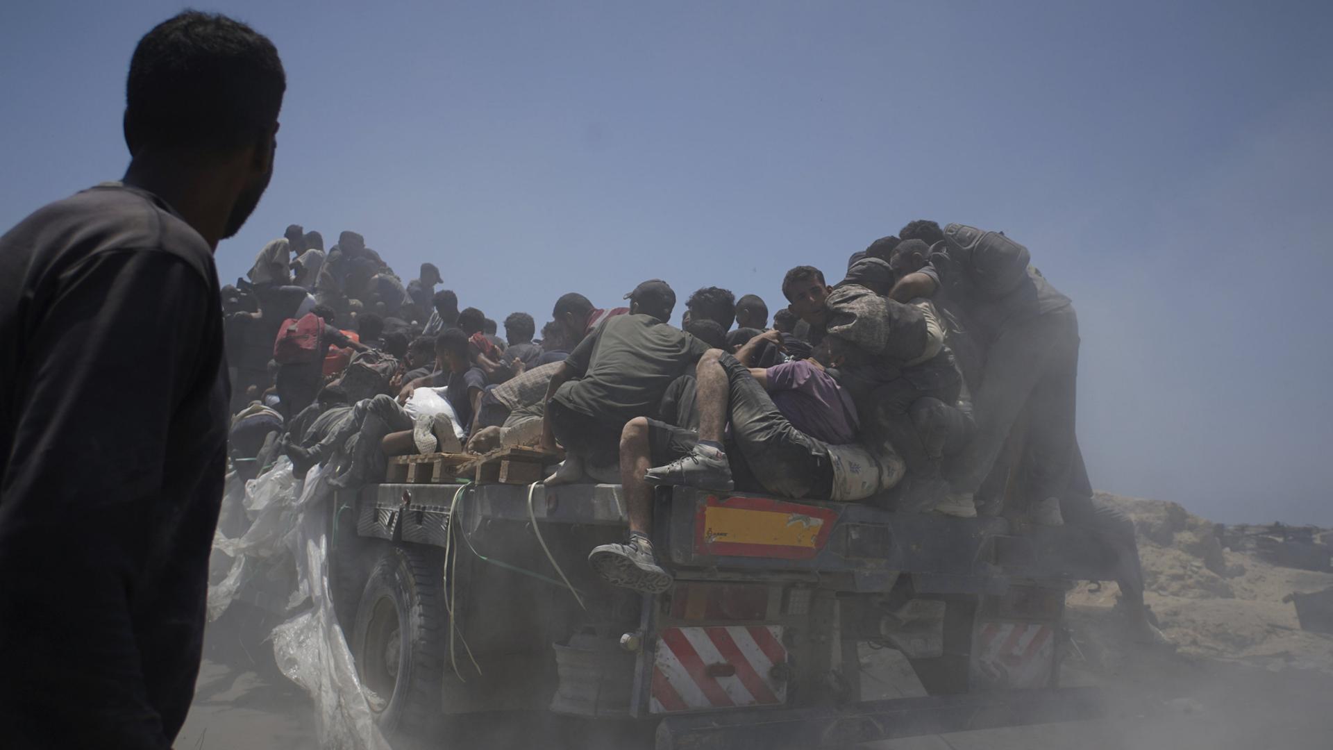 Bewohner des Gazastreifens halten sich an einem Lastwagen mit Hilfsgütern fest. | AP
