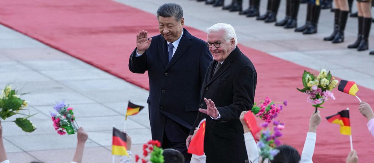 Xi Jinping und Frank-Walter Steinmeier winken Kindern während einer Begrüßungszeremonie vor der Großen Halle des Volkes in Peking zu.