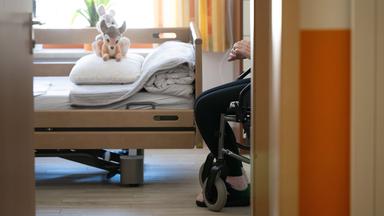 Ein Bewohner sitzt in einem Altenheim in seinem Zimmer in einem Rollstuhl.