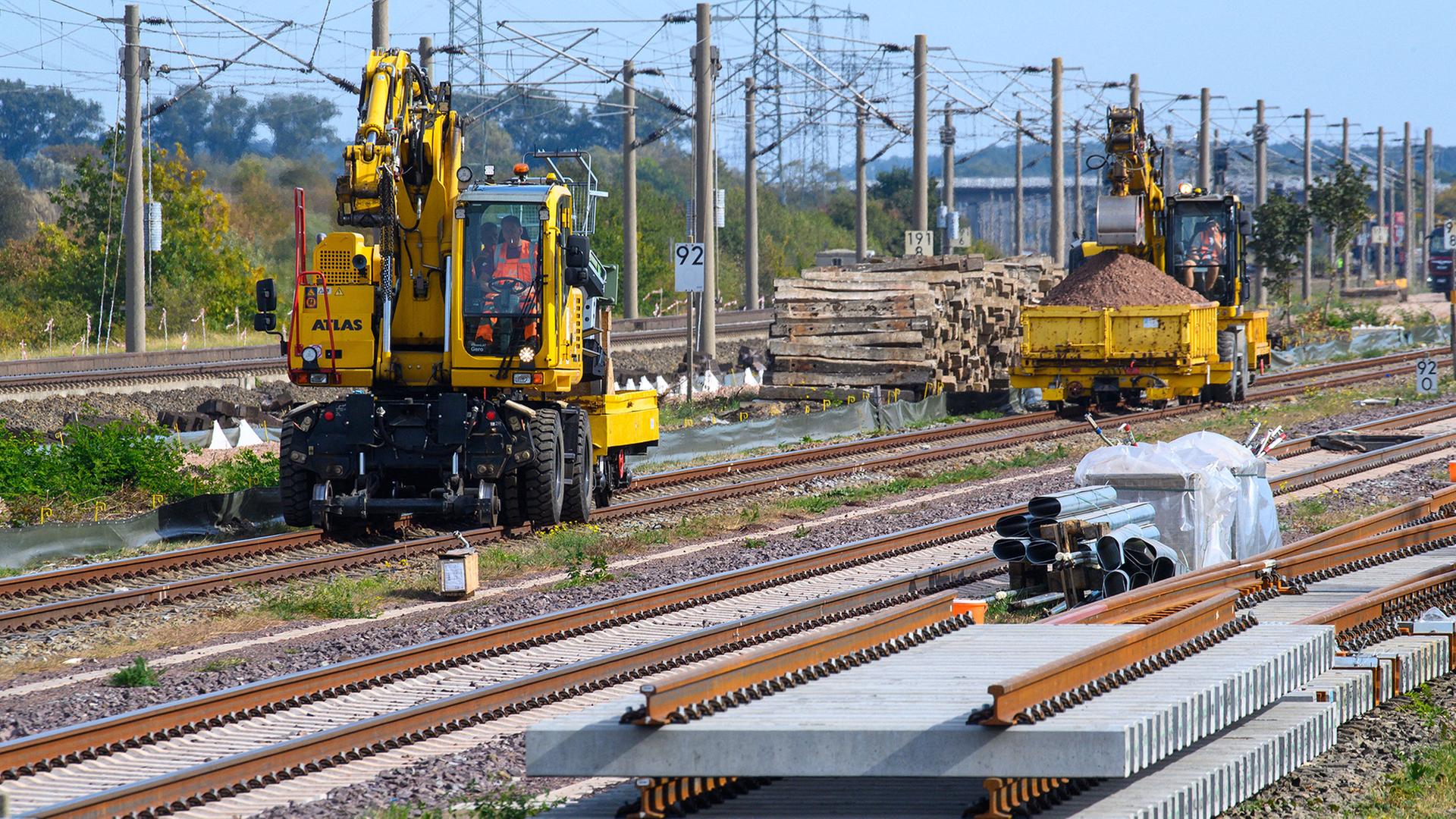 Gleisbaufahrzeuge rollen nahe des Bahnhofs Schönhausen an Gleisbauteilen vorbei. | Klaus-Dietmar Gabbert/dpa