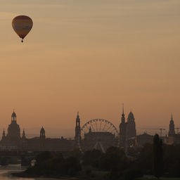 Ein Heißluftballon bei Sonnenaufgang über der Kulisse der Altstadt von Dresden.