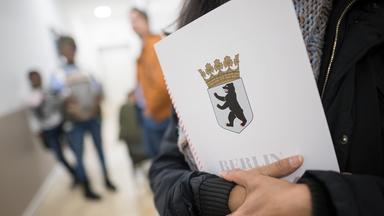 Eine Frau hält im Bürgeramt im Landesamt für Einwanderung eine Einbürgerungsurkunde in der Hand. 