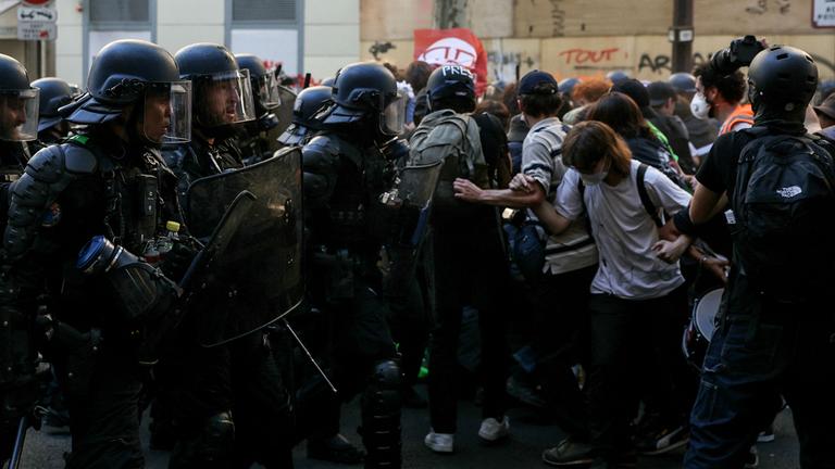 Polizisten und Demonstranten stehen sich in Paris auf einer Straße gegenüber.