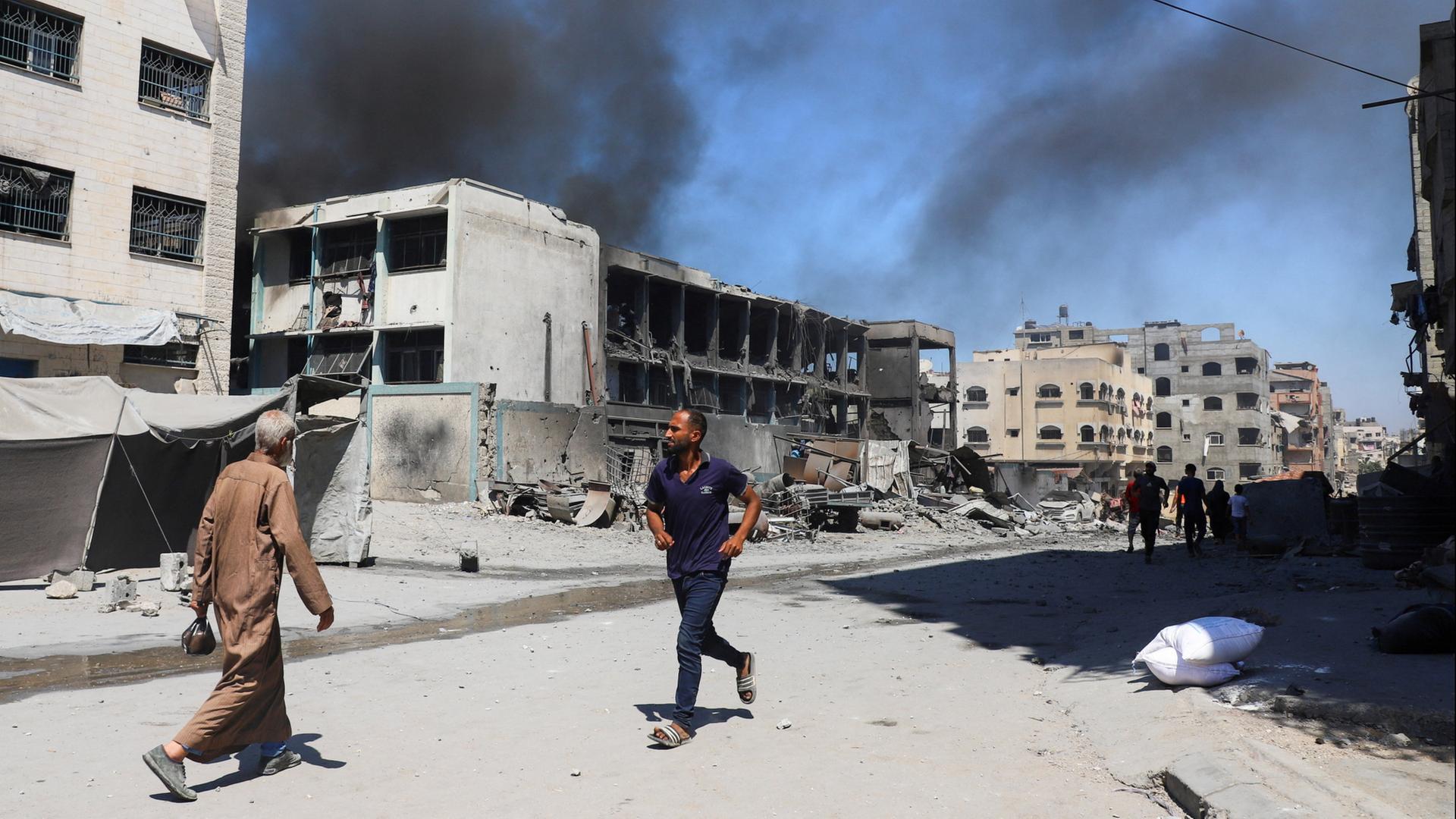 Zwei Personen laufen durch das zerstörte Flüchtlingslager al-Shati (Beach) im Gazastreifen. | REUTERS