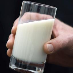 Eine Hand hält ein Glas mit Milch.