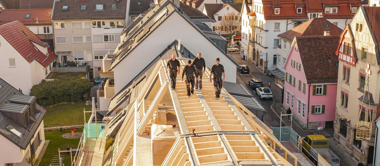 Workers on a new building roof overlooking an urban environment.