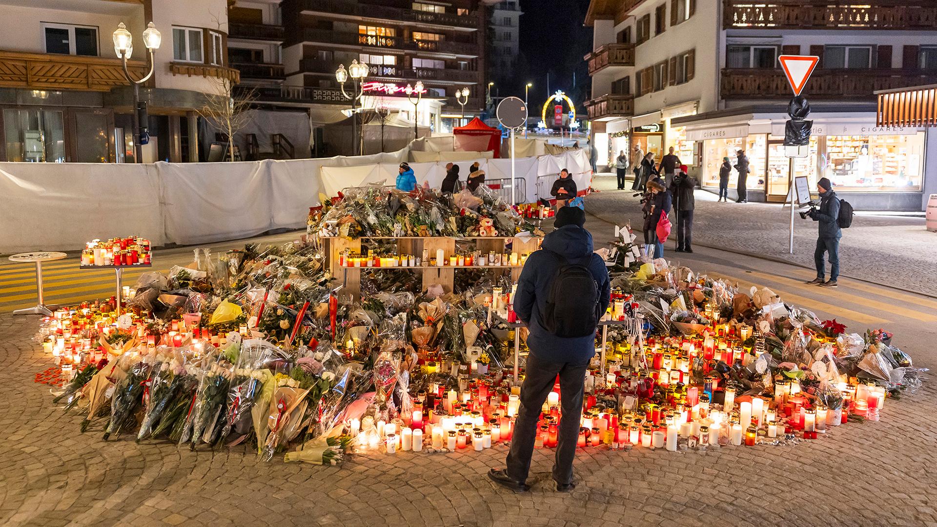 Menschen versammeln sich an einem Ort, an dem Blumen und Kerzen niedergelegt wurden. | EPA