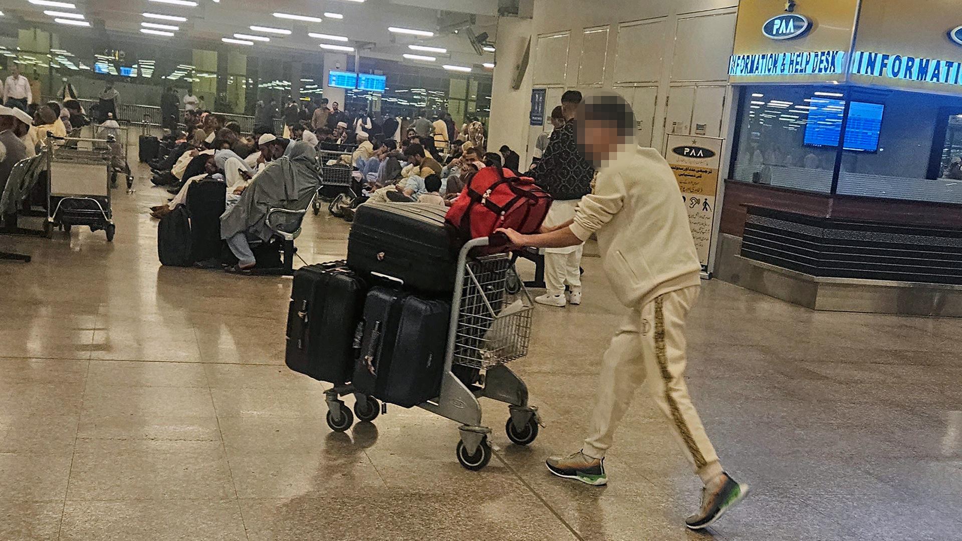 Personen mit Gepäck halten sich am Flughafen in der pakistanischen Hauptstadt Islamabad auf. | dpa
