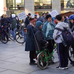 Zwei Frauen stehen mit drei Kindern in einer Gruppe. Sie halten zwei Fahrräder. Im Hintergrund tummeln sich viele weitere Menschen mit Fahrrädern.