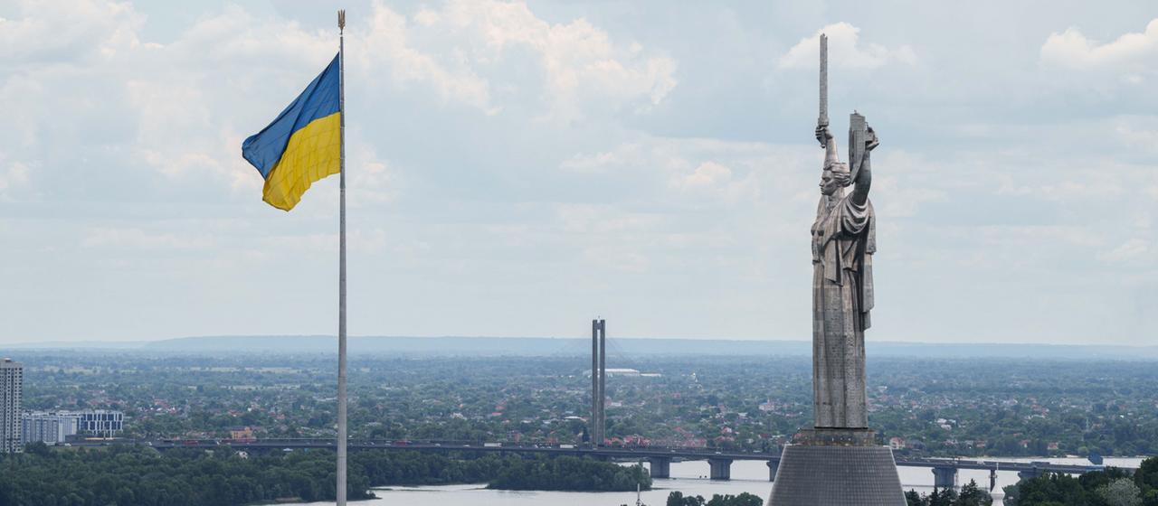 Die ukrainische Flagge weht neben der Mutter-Heimat-Statue in Kiew.