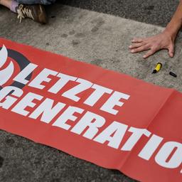 Ein Aktivist der Gruppe "Letzte Generation", der seine Hand selbst auf der Straße festgeklebt hat, blockiert eine Kreuzung in Göttingen.