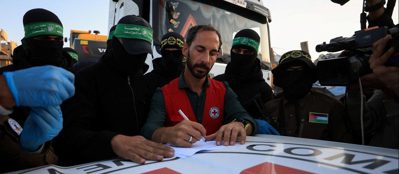  Hamas-Mitglieder übergeben die sterblichen Überreste an Mitarbeiter des Roten Kreuzes.