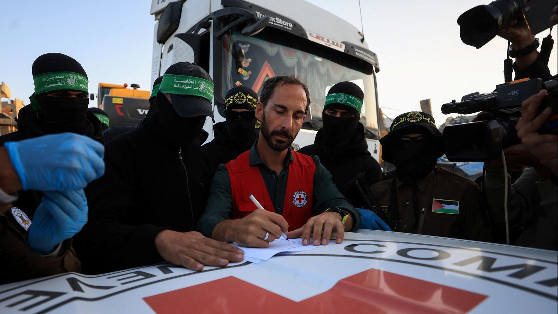  Hamas-Mitglieder übergeben die sterblichen Überreste an Mitarbeiter des Roten Kreuzes. | REUTERS