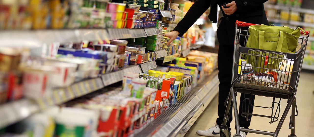 Ein Kunde bedient sich im Supermarkt-Regal.