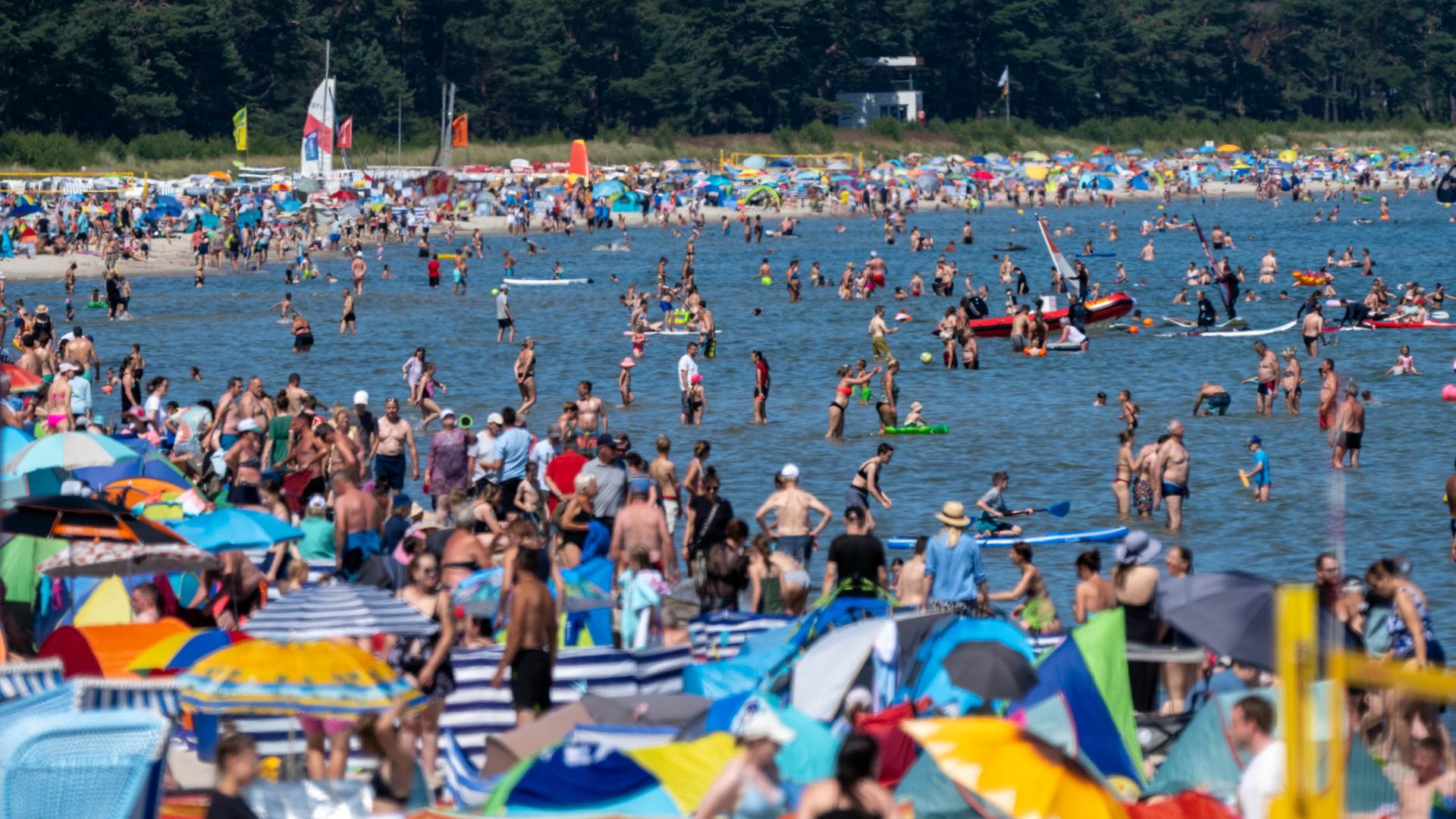 Touristen nutzen das hochsommerliche Wetter am Strand auf der Insel Rügen zum Sonnen und Baden.