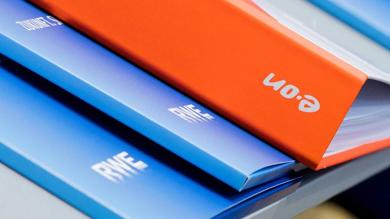Die Unternehmenslogos von RWE und E.ON sind auf Pressemappen zu sehen.