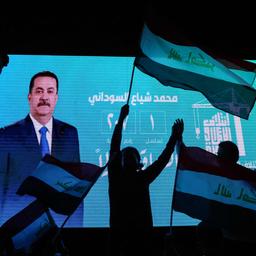 Anhänger des amtierenden irakischen Premierministers Mohammed Shia al-Sudani schwenken Nationalflaggen vor einem Bildschirm, auf dem sein Porträt zu sehen ist
