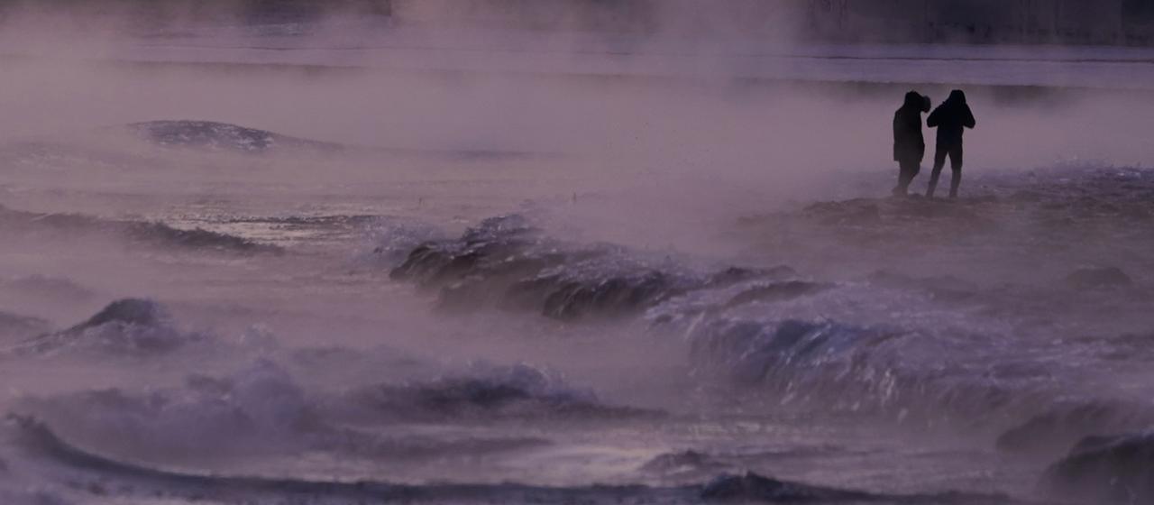 Menschen spazieren Chicago (USA) auf einem eisbedeckten Strand entlang des Ufers des Lake Michigan.