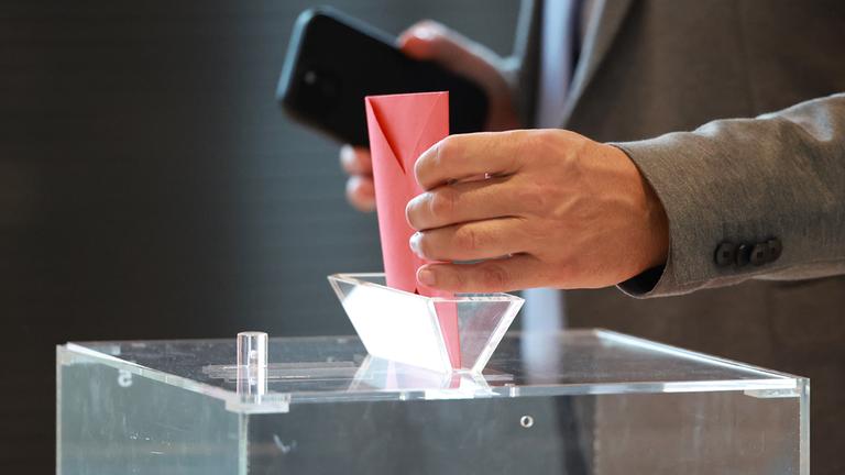 Ein Abgeordneter wirft seinen Stimmzettel in eine Wahlurne.