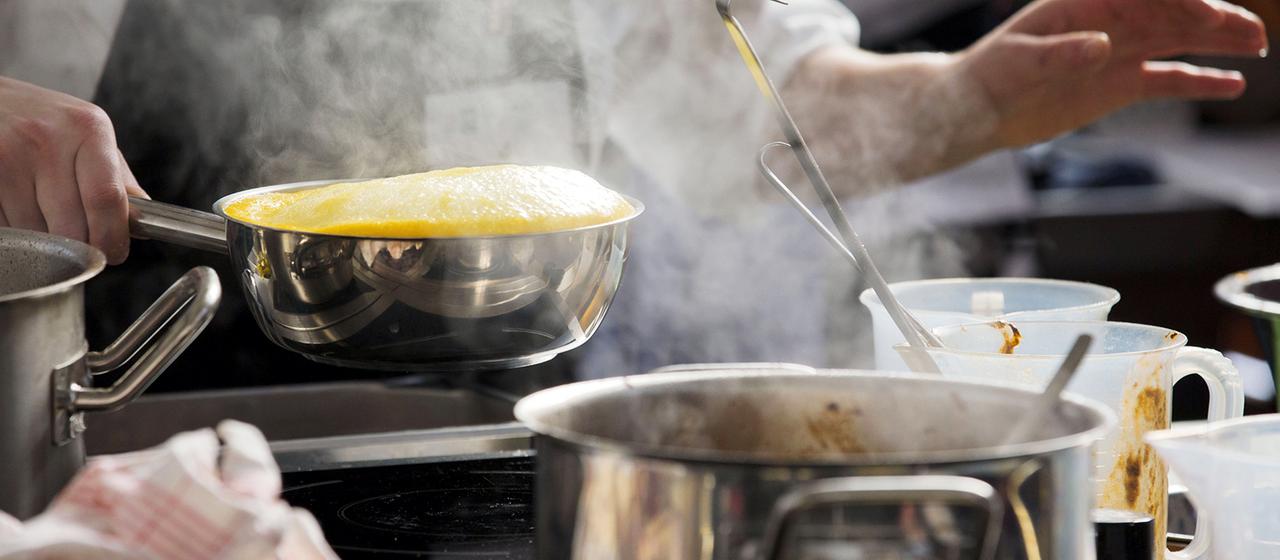 Ein Mensch arbeitet an einem Herd.