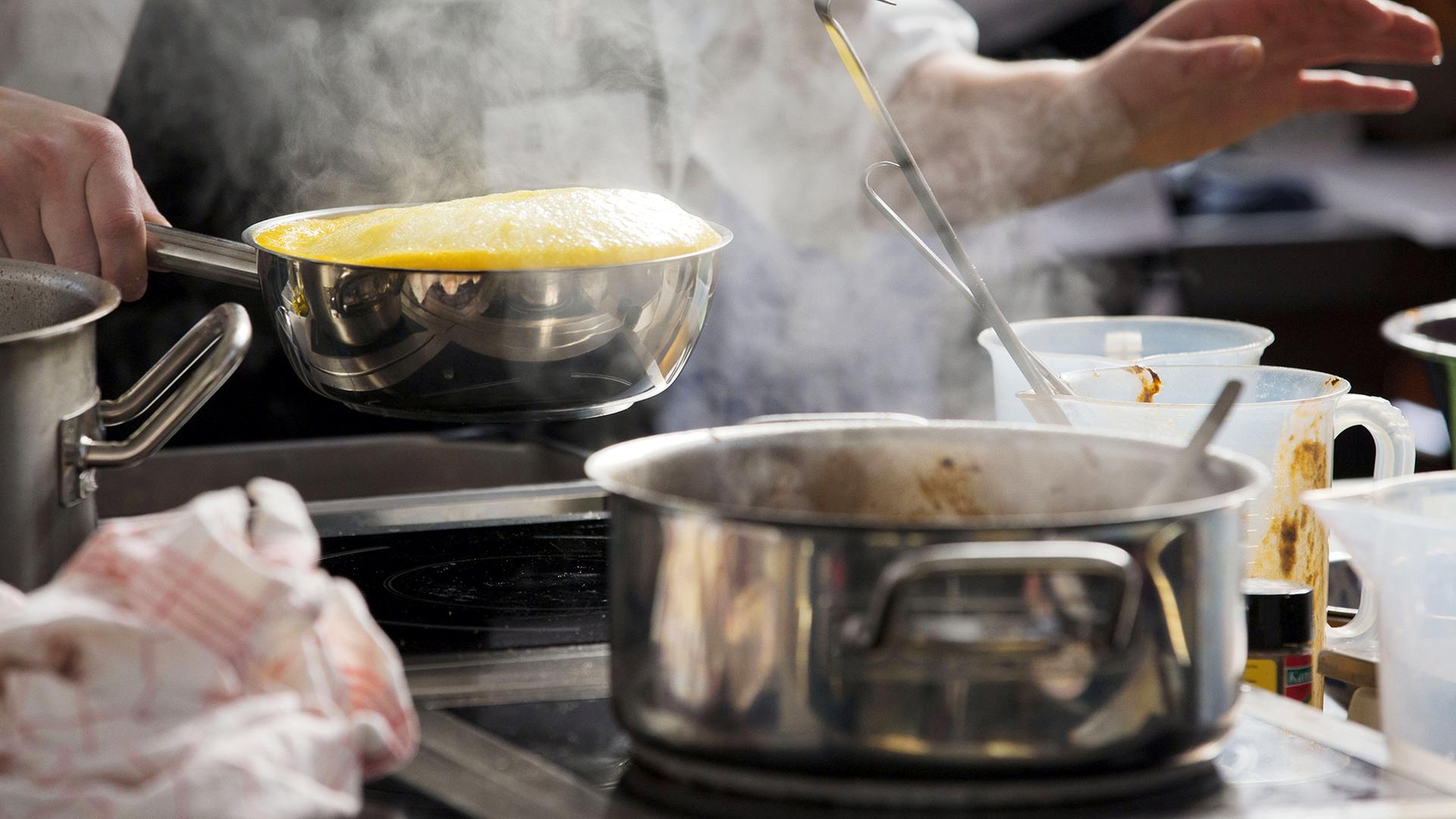 Ein Mensch arbeitet an einem Herd. | dpa