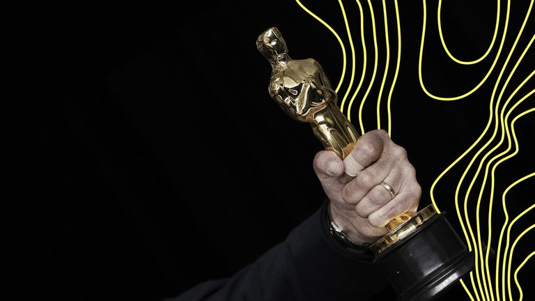Eine männliche Hand hält einen sogenannten Oscar, einen Filmpreis.