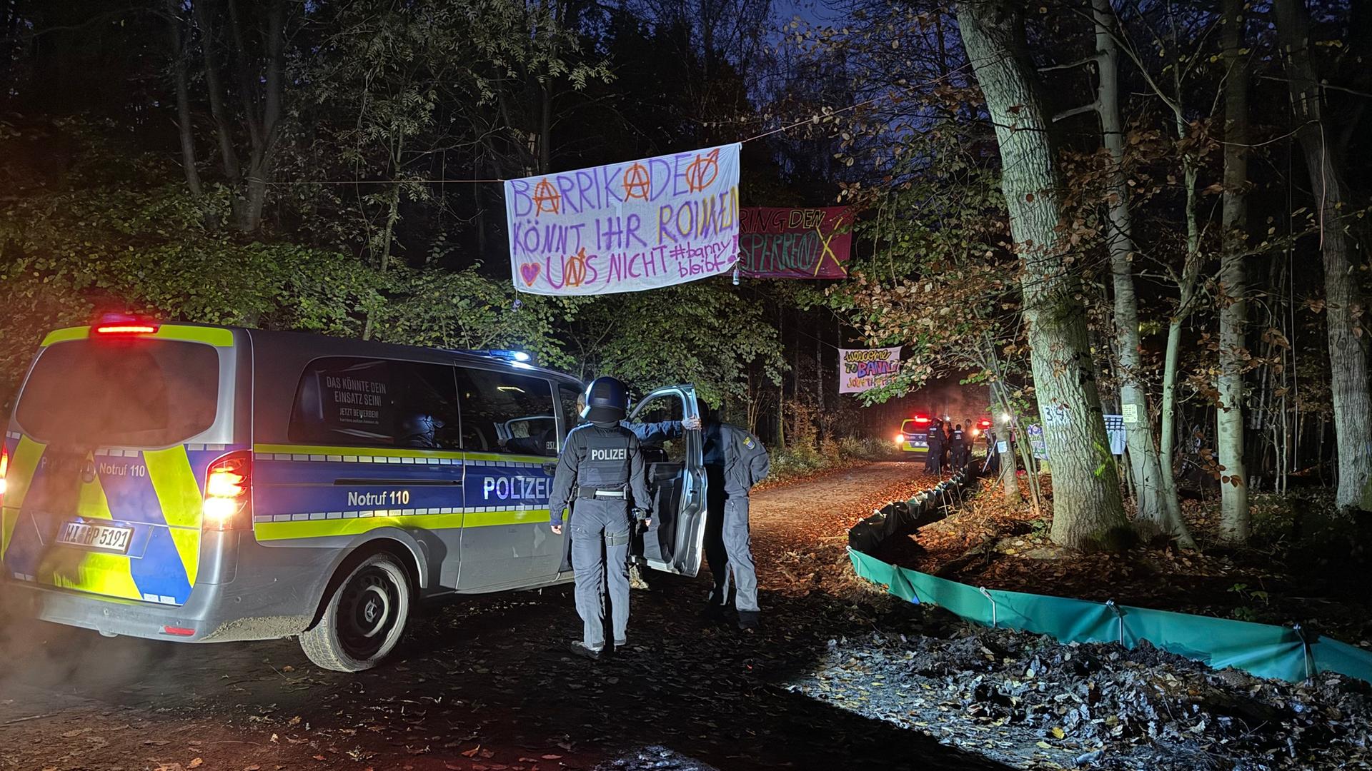 Polizeibeamte stehen neben einem Einsatzfahrzeug am Eingang eines Protestcamps im Langener Wald. | Luisa Schneider/hr