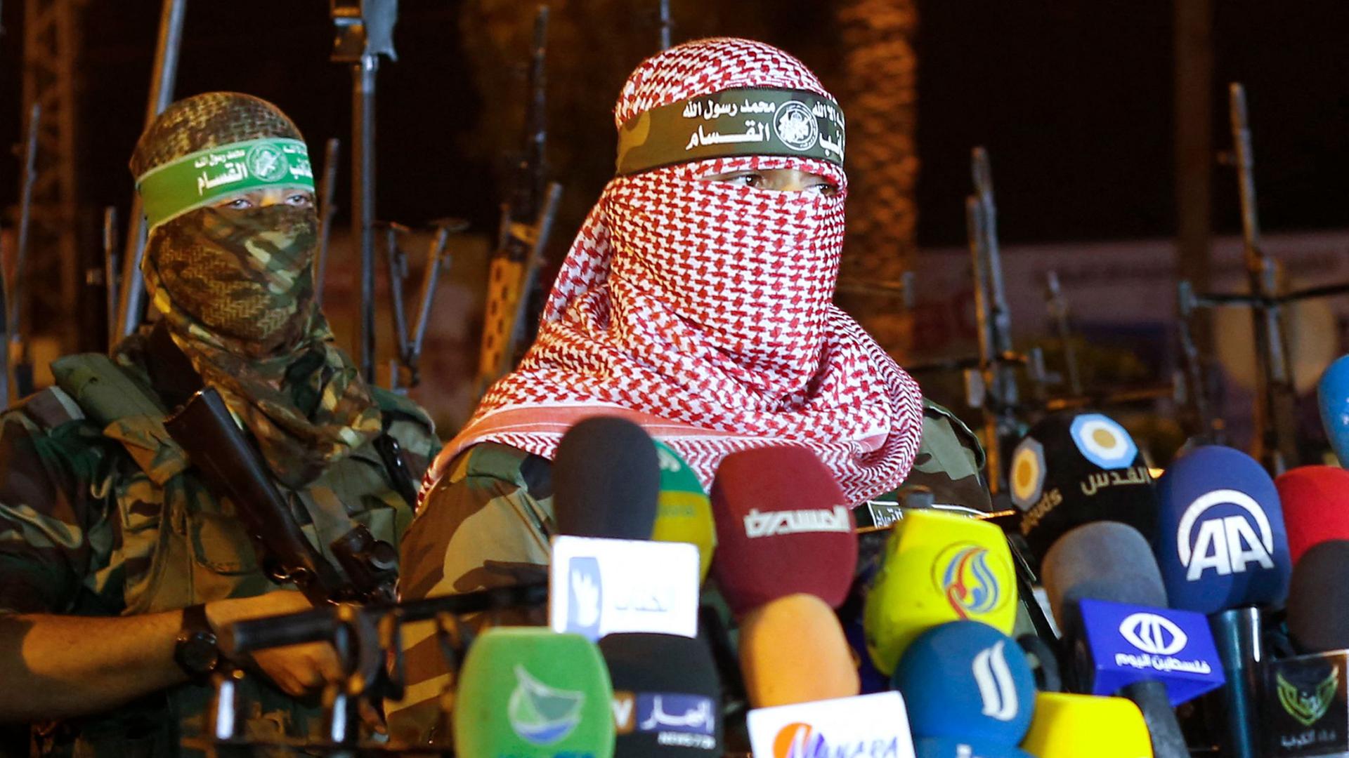 Das Bild aus dem Jahr 2015 soll den Hamas-Sprecher Abu Obeida zeigen, der sich vor Mikros äußert. Sein Gesicht ist durch ein weiß-rotes Palästinensertuch verhüllt. | AFP