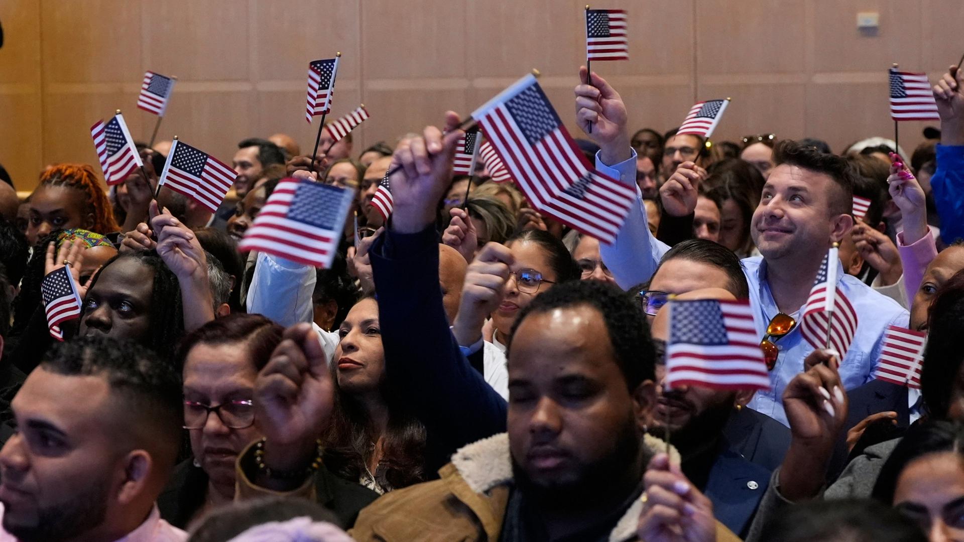 Menschen schwenken Fahnen der USA bei einer Einbürgerungsfeier | AP