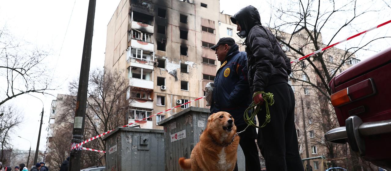 Anwohner stehen in der Nähe eines zerstörten Wohnhauses in Saporischschja.