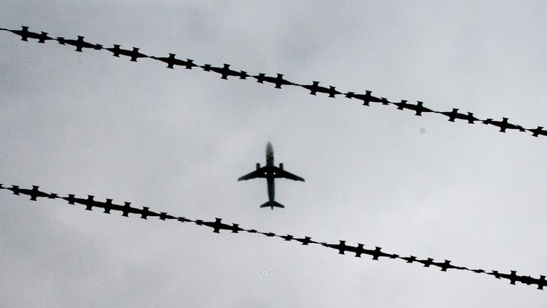 Ein Flugzeug ist hinter Stacheldraht zu sehen.