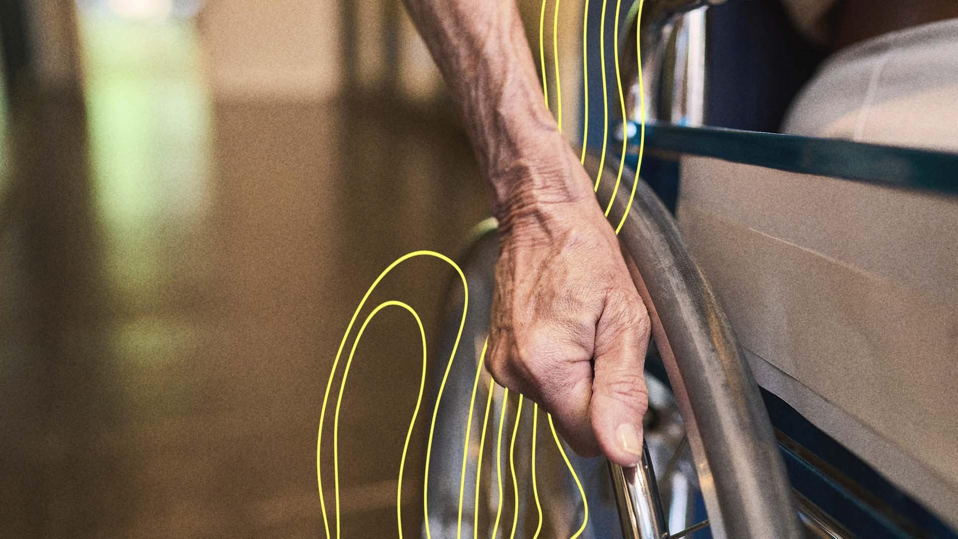 Eine alte Dame hat ihre Hand am Rad vom Rollstuhl. | picture alliance / Zoonar | Robert Kneschke
