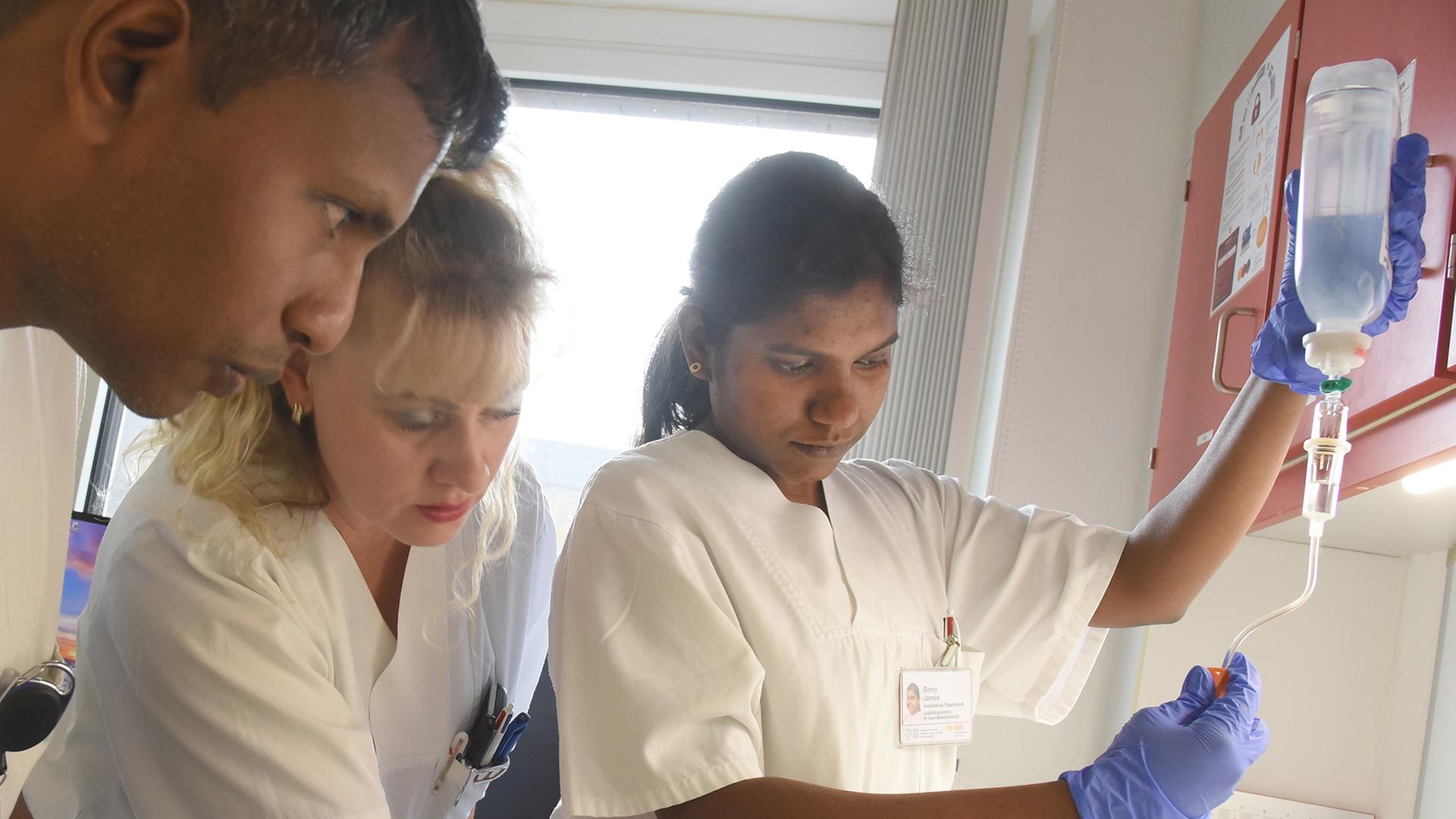 Eine Praxisanleiterin erklärt  angehenden indischen Pflegefachkräften das Vorbereiten einer Infusion. | picture alliance/dpa